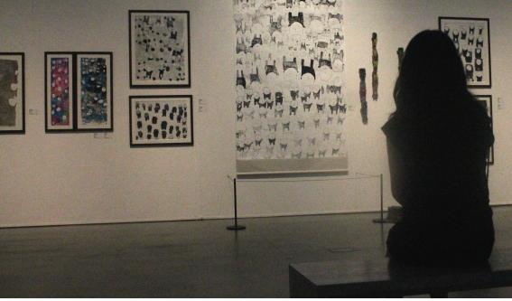 한 관람객이 전시된 작품을 보며 사색에 잠겨 있다.