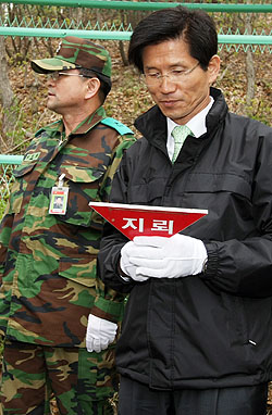 펜스 절단식 후 떨어진 ‘지뢰’ 표시 팻말을 손에 든 김 지사. 