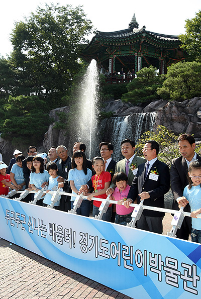 이날 개관식은 김문수 경기도지사와 어린이, 다문화가족 등 800여명이 참석한 가운데 어린이박물관 광장에서 진행됐다. 김문수 경기도지사와 내빈들이 어린이들과 함께 터치버튼 퍼포먼스를 하기 위해 단상 앞에 서 있다.   