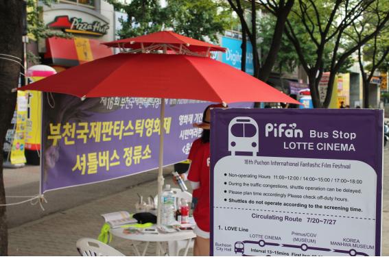 행사장소 앞 셔틀버스 정류소의 현수막과 표지판이 보인다.