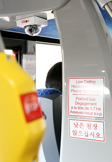 승객의 안전을 위한 CCTV 카메라와 함께 낮은 천장에 관한 안내 문구가 보인다.