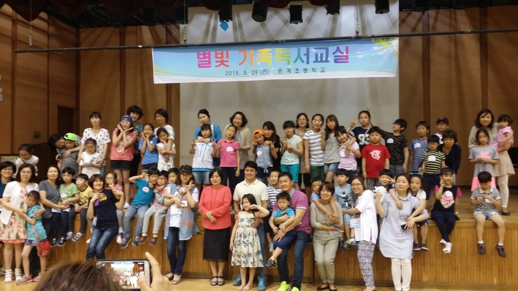 별빛 가족 독서교실에 참여한 가족들이 학교 체육관에 모여 단체사진을 찍고 있다