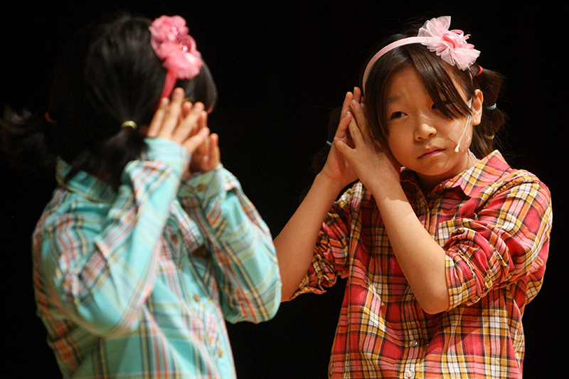 아이들이 무대에서 뮤지컬 공연을 하고 있다.