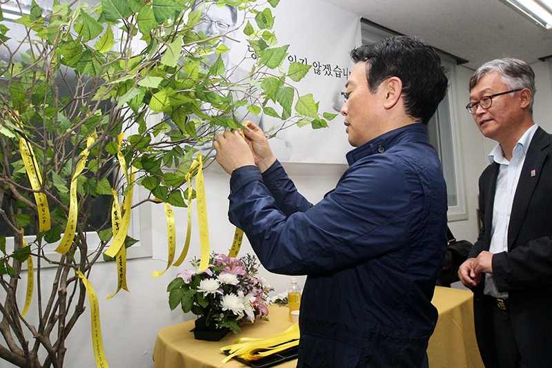 남경필 지사가 고(故) 이근호 따복공동체지원센터장을 기리는 나무에 노란 리본을 매달고 있다.