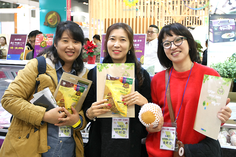 팸투어 참가자들이 ‘G푸드비엔날레 2015’에서 G마크 인증 농특산물을 들고 웃어 보이고 있다.