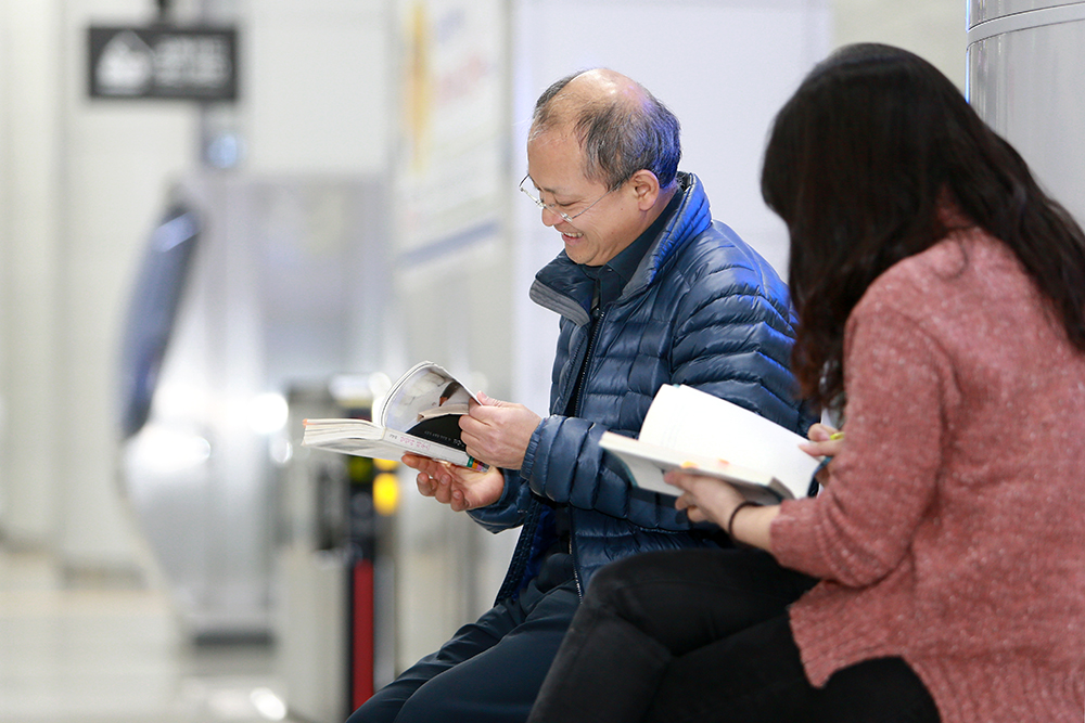도민들이 광교중앙역에 설치된 지하철 서재에서 책을 읽고 있다.