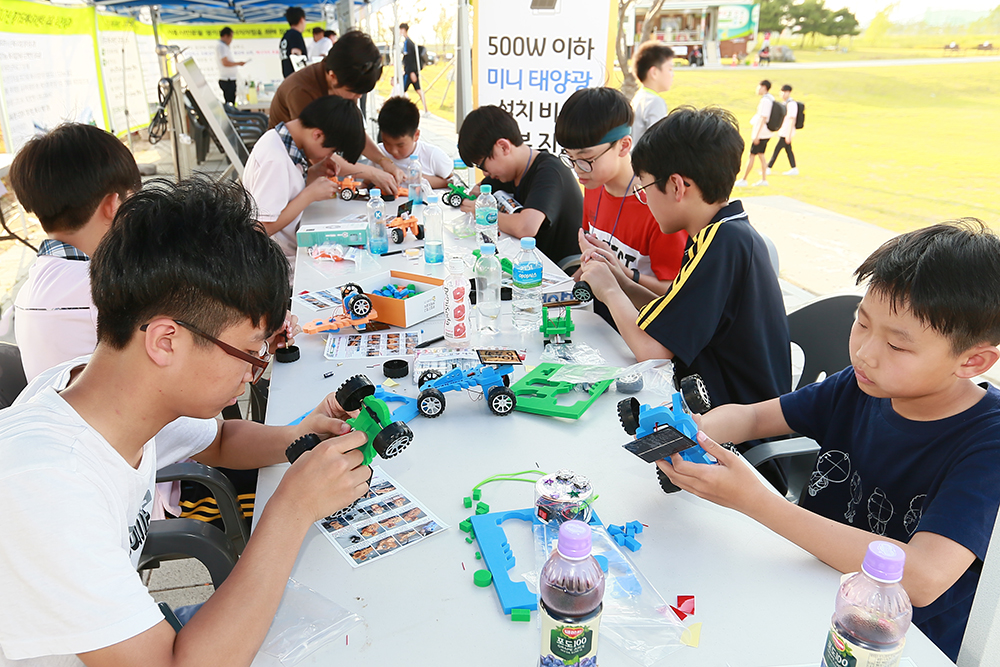 아이들이 행사장내 마련된 체험 부스에서 태양광 자동차를 만들어 보고 있다.