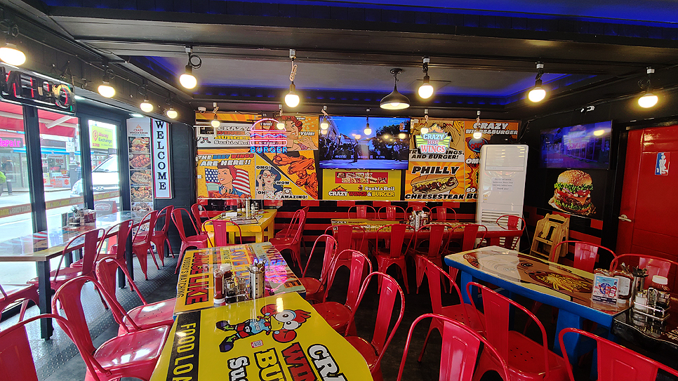 식당 내부에는 각양각색의 포스터들이 벽을 장식하고, 컬러풀한 미국식 테이블과 함께 클래식한 레드 컬러로 도색된 의자들이 배치되어 있습니다.