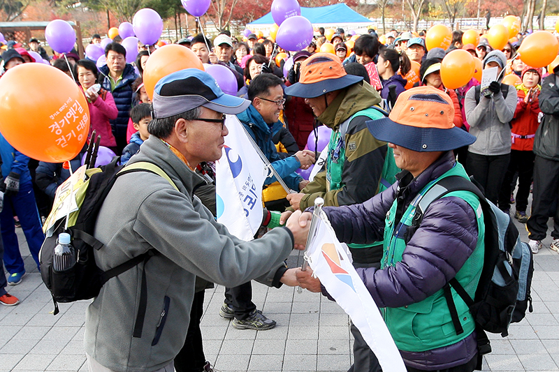 7일부터 14일 열린 ‘경기옛길 따라 릴레이 종주’ 종주단원이 걷기대회 출발 전 참가 대표에게 경기옛길 홍보 깃발을 전달하고 있다.